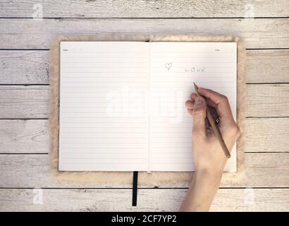 Top view wooden office desk table with blank notebook and hand with a pen. Office supplies with copy space, flat lay Stock Photo