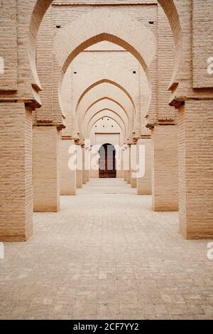 Aged stone building with columns and ornamental carved arches in old city Marrakesh in Morocco Stock Photo