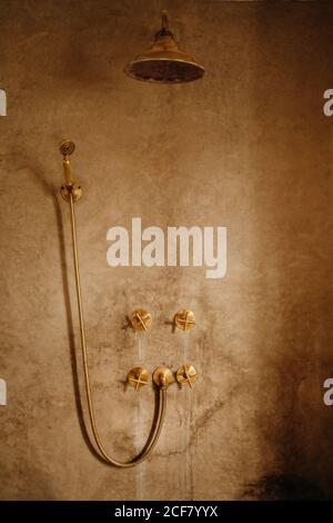 Interior of vintage bathroom with shabby stone wall and golden metal taps and shower head in Moroccan hotel Stock Photo