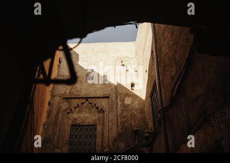 From below of aged stone house with shabby walls and ornamental windows located on street of ancient Marrakesh city in Morocco Stock Photo