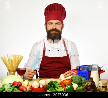 Chef cuts the vegetables into meal. Preparing dishes concept. Bearded man uses a knife and cooks. Stock Photo