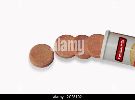 Pill bottle spilling health supplement, calcium pills (effervescent tablets) on to surface isolated Stock Photo