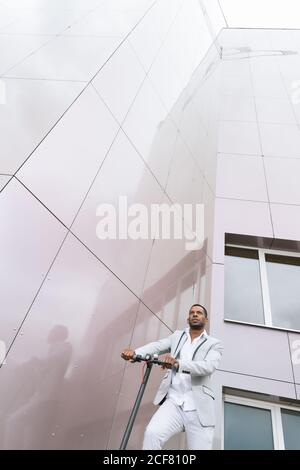 Black man in suit on electric scooter in business center Stock Photo