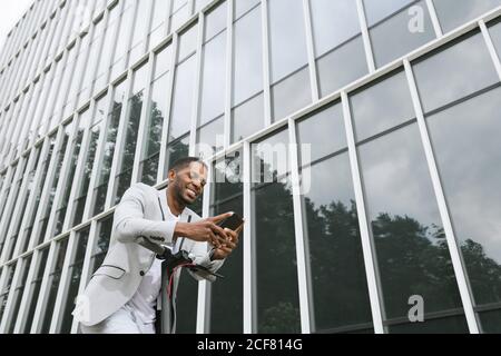 Smiling black man riding scooter and speaking on smartphone Stock Photo