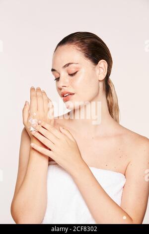 Delighted female applying recovery cream on hands Stock Photo