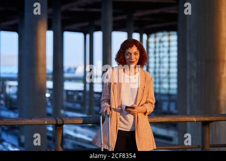 Smiling young Woman holding phone at station Stock Photo