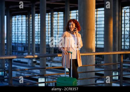 Smiling young Woman talking on phone at station Stock Photo