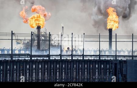 Weathered industrial buildings and pipes emitting smoke and flames at coking factory Stock Photo