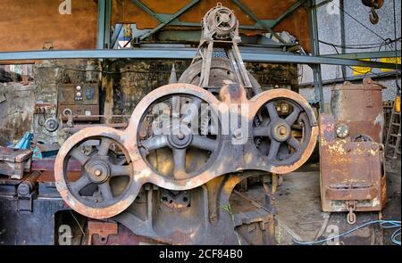 Old used rusty mechanism made of steel discs of various diameters mounted on metal device in dirty abandoned factory building Stock Photo
