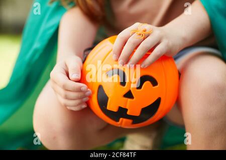 Close-up of girl sitting outdoors with toy pumpkin in her hands Stock Photo