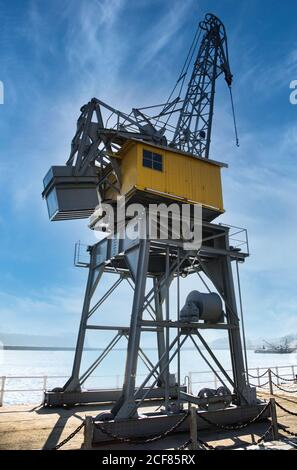 Low angle of contemporary container crane located on quay in Port of San Esteban de Pravia against cloudy blue sky on sunny day in Spain Stock Photo