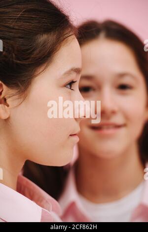 Pretty little twin sisters posing. One is facing side other facing forward. Stock Photo