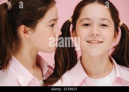 Beautiful little twin sisters posing. One is facing side other facing forward. Stock Photo