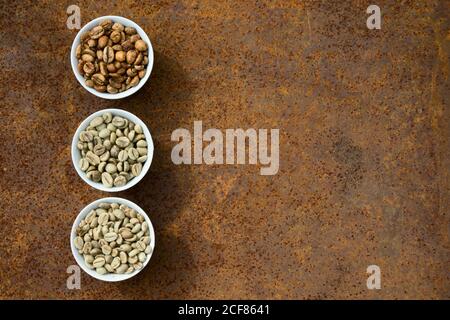 Flat lay  of   brown and green coffee beans in ceramic bowl  on  rustic iron  background Stock Photo