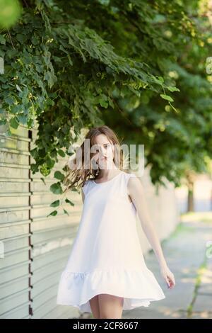 Lovely little girl in a very short white summer dress sits on her