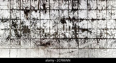 Weathered white tiles with black stains and cracks covering wall inside desolate building Stock Photo