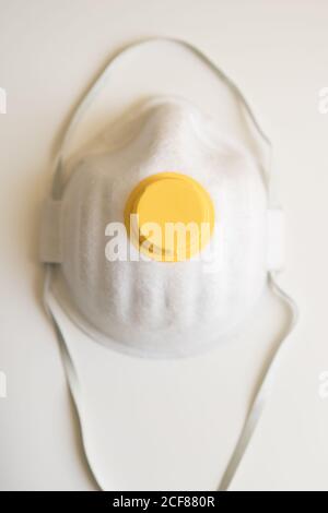 From above of facial protection mask placed on white background isolated as symbol of protection against coronavirus pandemic and other infections Stock Photo