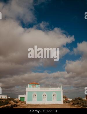 Exterior of small house with blue wall and white elements on yard under blue sky with clouds, Canary Island Stock Photo