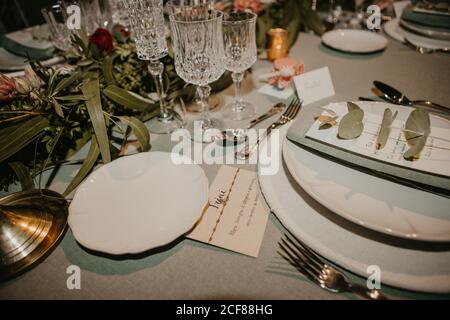 Various dishware and name card arranged with flowers and elegant glassware on table for wedding reception Stock Photo