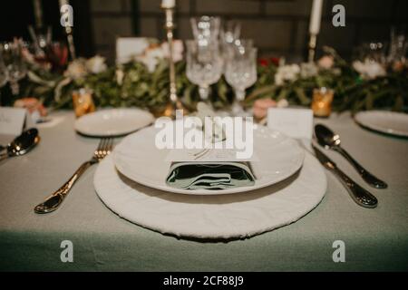 Various dishware and name card arranged with flowers and elegant glassware on table for wedding reception Stock Photo