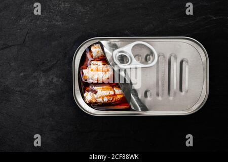 Top view of canned sardines in oil placed on slate board against black background Stock Photo