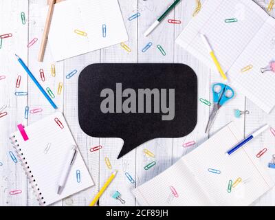 Empty black Bubble chalkboard on wooden background. Table with notebooks, pens, paper clips Stock Photo