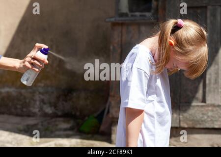 Mother applying mosquito and bugs repellent to her daughter. Children, kids and chemical repellents spraying concept, mist Stock Photo