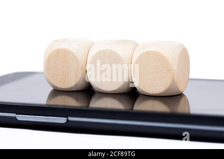 Three blank wooden cubes laying on a smartphone screen. Empty dice with icon space placed on a mobile phone display. 3 elements, technology cubes Stock Photo