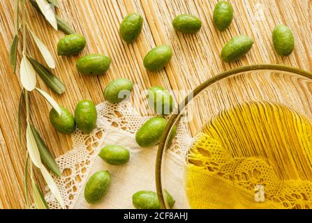 Still life with organically grown olives freshly picked from the olive tree on a textured wooden board and a bowl with olive oil. Stock Photo
