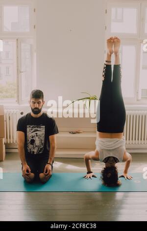 Peaceful hipster couple practicing yoga positions while exercising in modern apartment Stock Photo