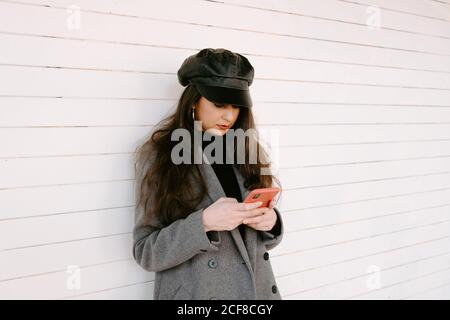 Woman using smartphone near wall Stock Photo