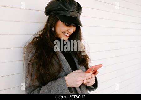Happy Woman using smartphone near wall Stock Photo