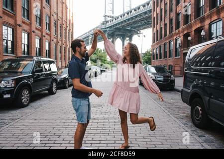 Couple in love in summer wear holding hands and dancing on sidewalk in New York during city stroll Stock Photo