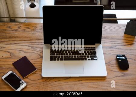Modern netbook placed on wooden table with smartphone and mouse in cozy coffee shop Stock Photo