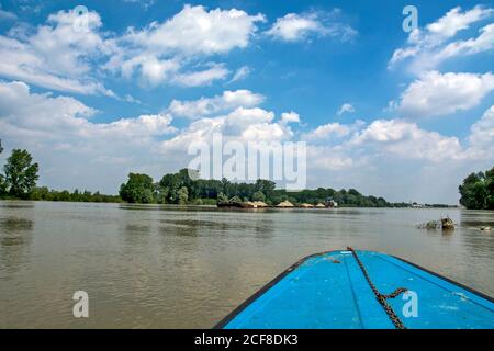 A large and powerful river boat pushes barges loaded with sand and gravel along the river. The ship sails powerfully in the middle of the river. Stock Photo