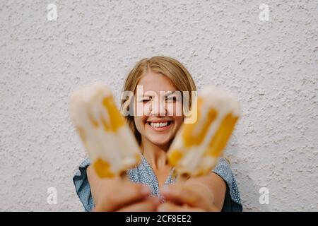 Female blinking eyes and making funny grimace faces with tasty ice lollies on sticks on white background Stock Photo