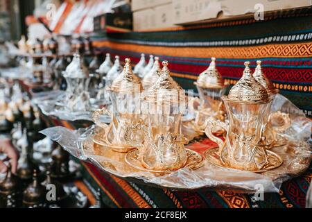 Set of glass traditional Turkish teapots with golden ornaments composed on tray on patterned oriental fabric at market in Istanbul Stock Photo