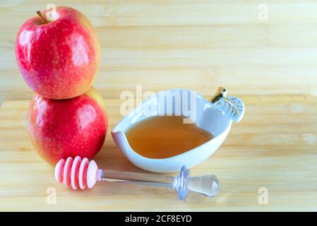 Jewish holiday Rosh Hashana background with honey and apple on wooden table. During the Jewish New Year Rosh Hashanah customary eat sliced apples dipped in honey symbol sweet new year. Stock Photo
