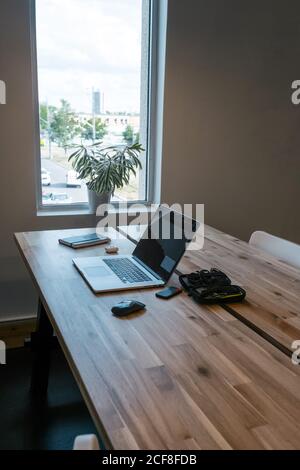 Netbook and mouse placed on wooden table with notebook and wireless earphones in creative workspace Stock Photo