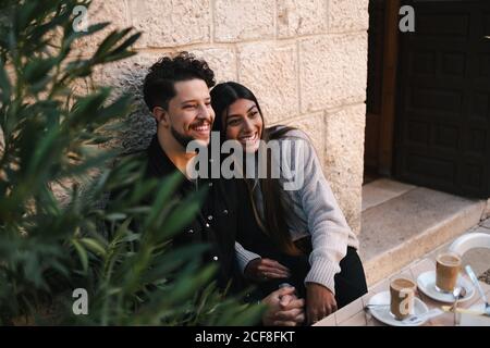 Cheerful boyfriend and girlfriend sitting while having a coffee with milk during city stroll Stock Photo