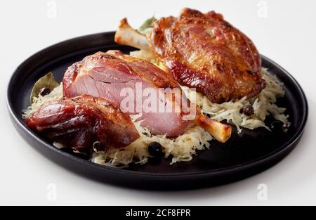 Double serving of German ham hock or Eisbein with traditional sauerkraut on a plate over white Stock Photo
