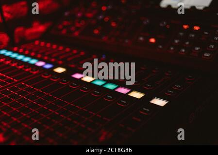 From above bright vivid DJ music console with glowing colorful buttons in dark club during play Stock Photo