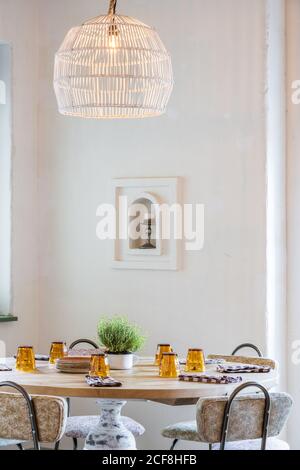Classic lampshades with warm light hanging over set wooden table in light hall Stock Photo