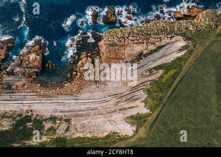 Amazing aerial landscape of steep rocky shore and breathtaking wavy ocean in cloudy day in Pielagos, Cantabria, Santander, Spain Stock Photo