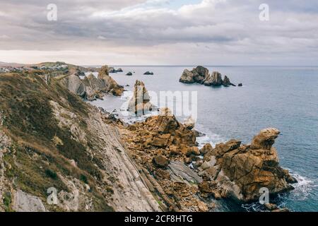 Amazing aerial landscape of steep rocky shore and breathtaking wavy ocean in cloudy day in Pielagos, Cantabria, Santander, Spain Stock Photo