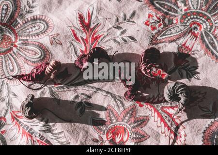 From above dead tree leaves on bright floral table cloth in sunlight Stock Photo
