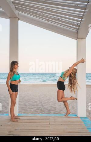 Inspired women making acroyoga first hollowback handstand on beach Stock Photo