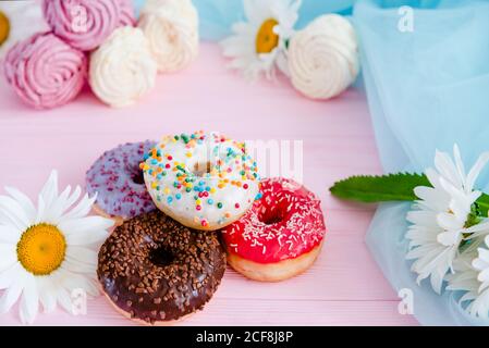 Variety of doughnuts and marshmallow on pink background. Junk food. Sweet confectionery. Stock Photo