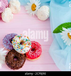 Variety of doughnuts and marshmallow on pink background. Junk food. Sweet confectionery. Stock Photo