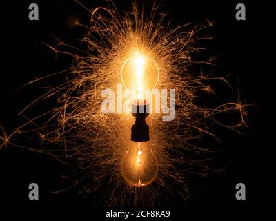 Light bulb with sparklers from behind on black background Stock Photo
